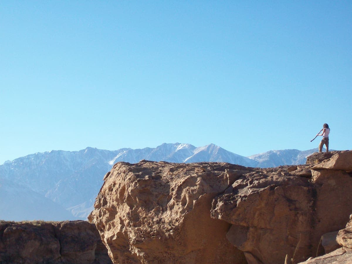 Josh on an open mountain ridge facing snow peaks